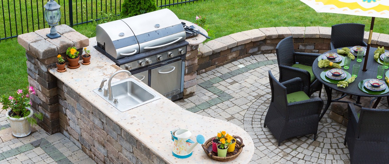 Large outdoor patio kitchen featuring a sink and grill.